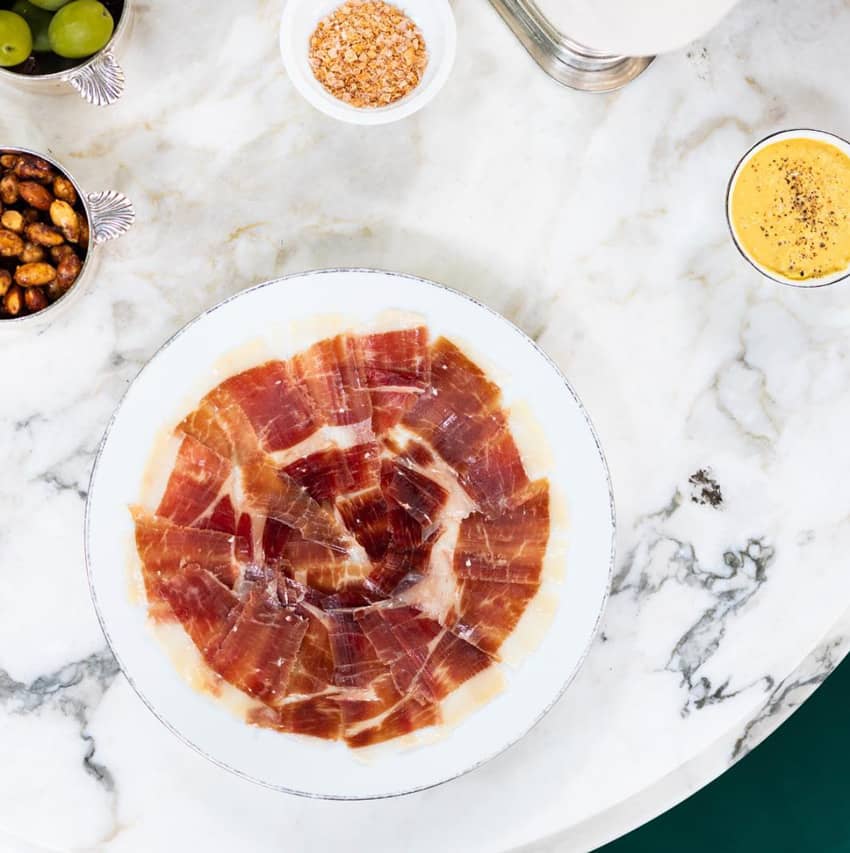 Flatlay plate of prosciutto on marble table