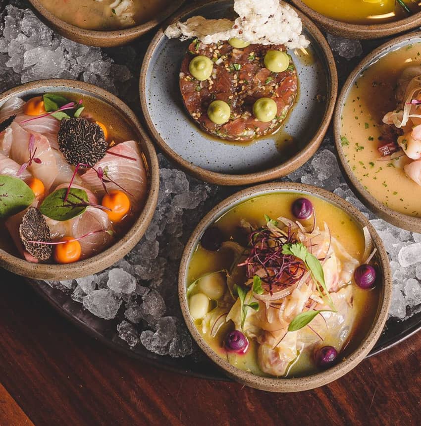 four bowls with seafood dishes on ice plate