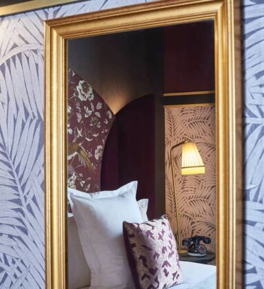 large mirror reflecting bed and lamp purple tones