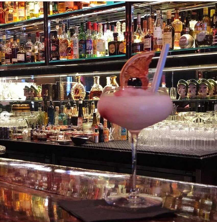 pink foamy cocktail on bar and lounge